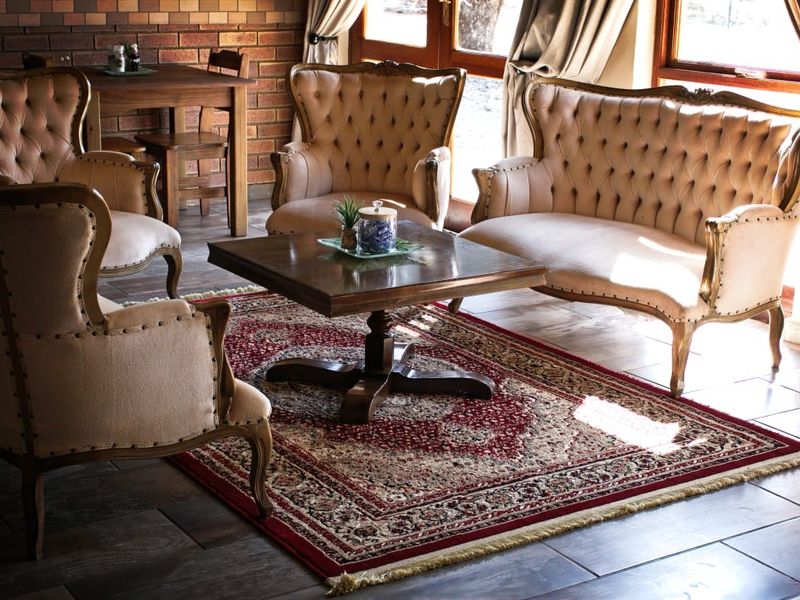 A cozy living area featuring exposed brick walls, tiled flooring, and timber-framed glass doors that provide natural light.
