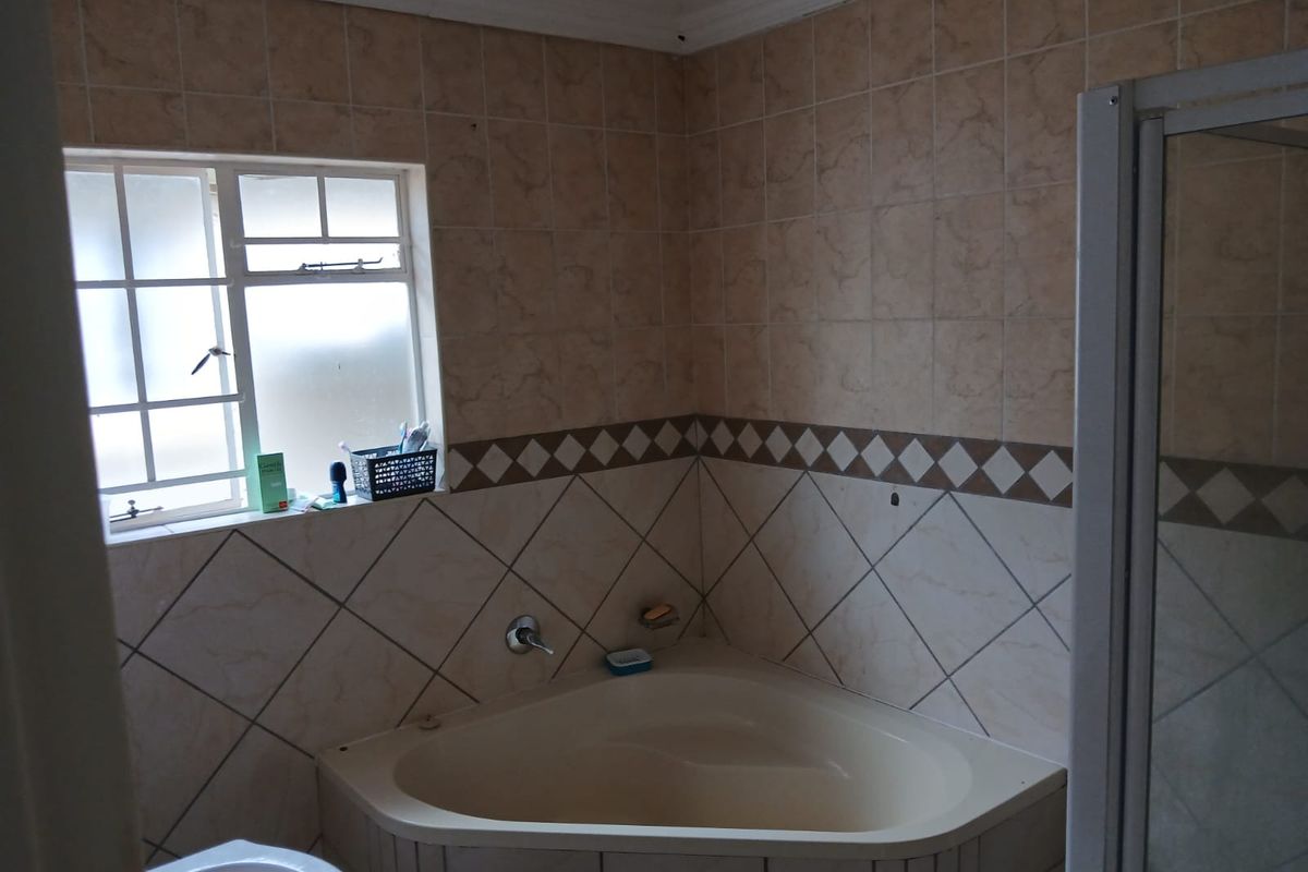 A dated bathroom featuring a corner bathtub, shower enclosure, and pedestal basin, finished with neutral wall tiling.
