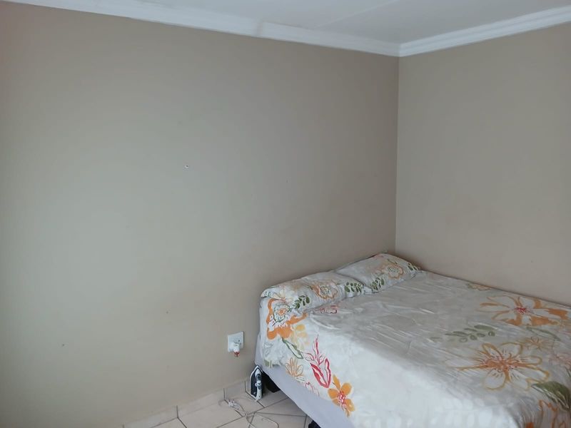 A simple bedroom featuring tiled flooring and coved ceiling details, providing a functional space ready for personalization.