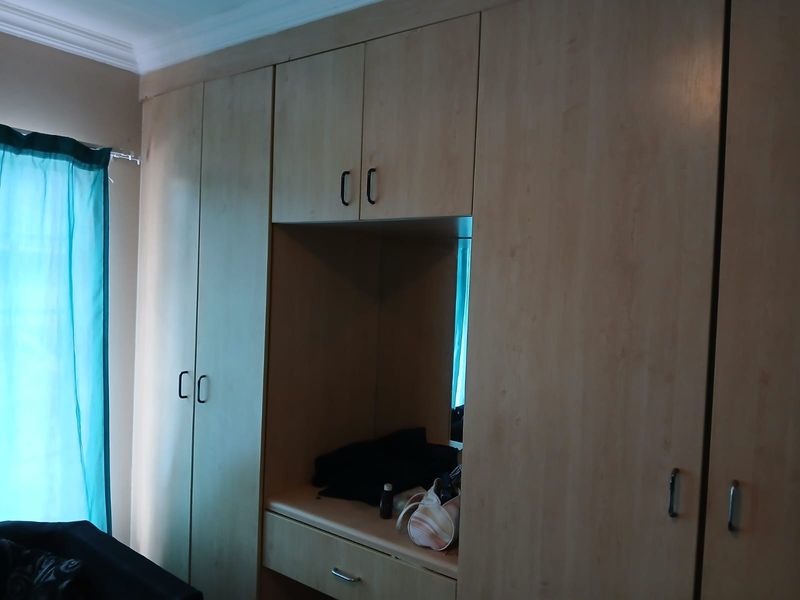 Bedroom featuring extensive light wood-finish built-in cupboards with a central recessed vanity or storage nook.