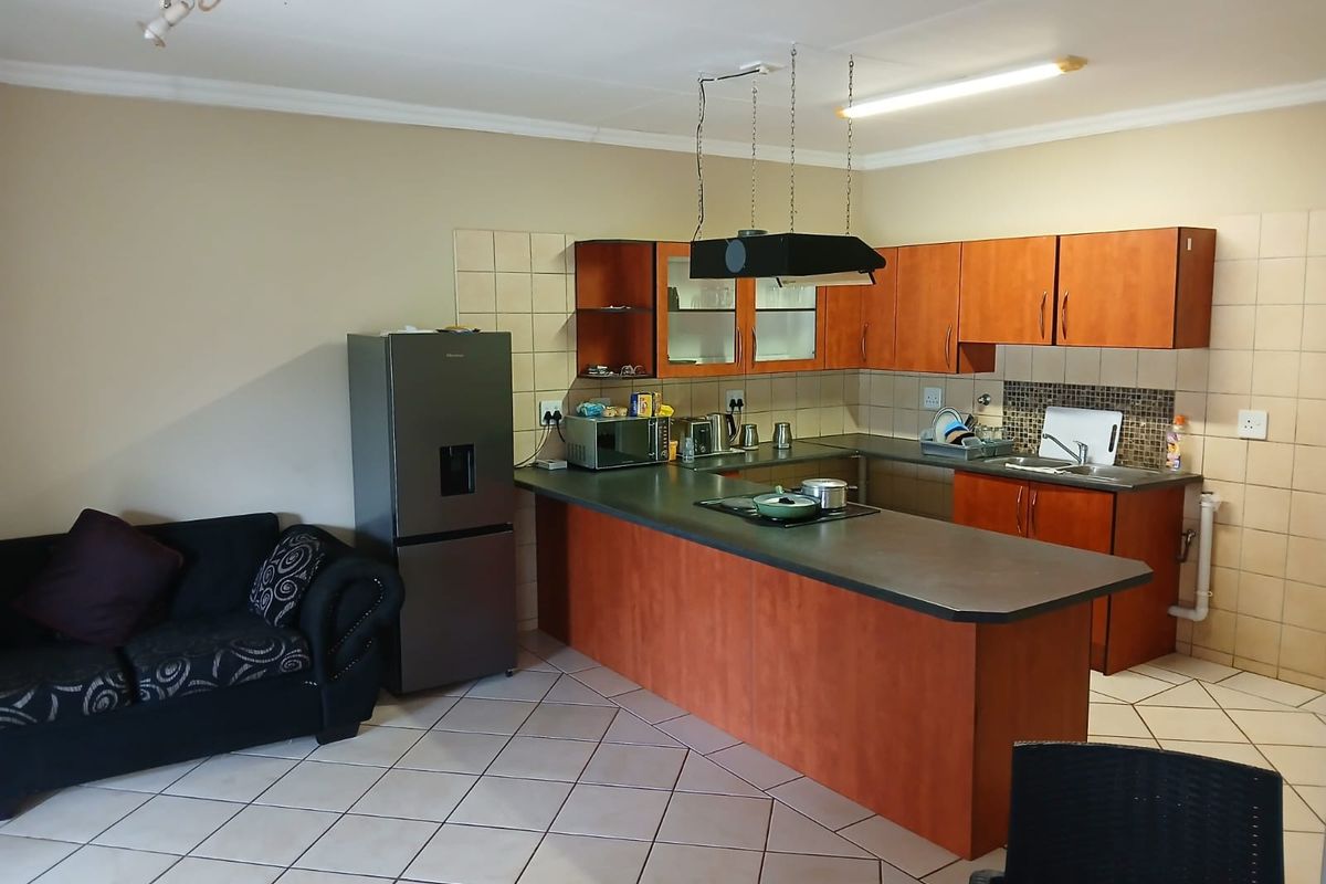 Open plan kitchen featuring laminate cabinetry, a breakfast bar with integrated hob, and tiled flooring, seamlessly connecting to the living area.