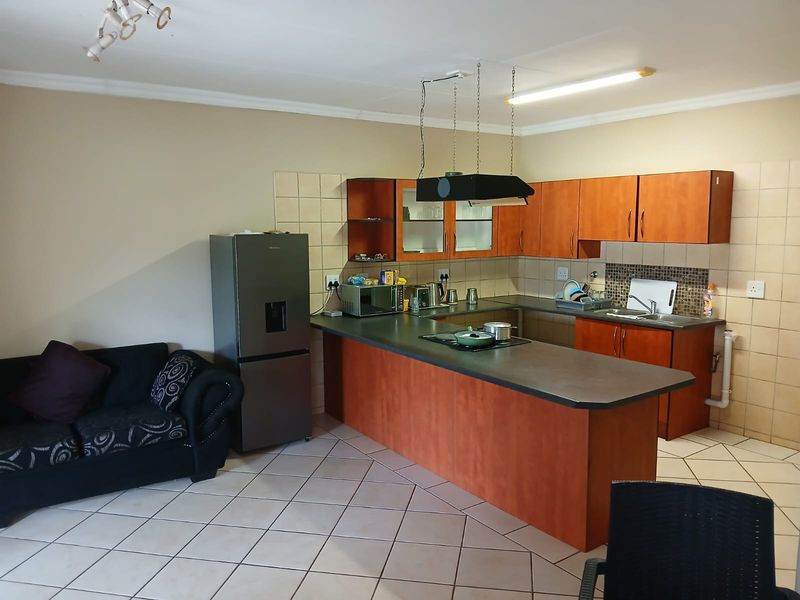Open plan kitchen featuring laminate cabinetry, a breakfast bar with integrated hob, and tiled flooring, seamlessly connecting to the living area.