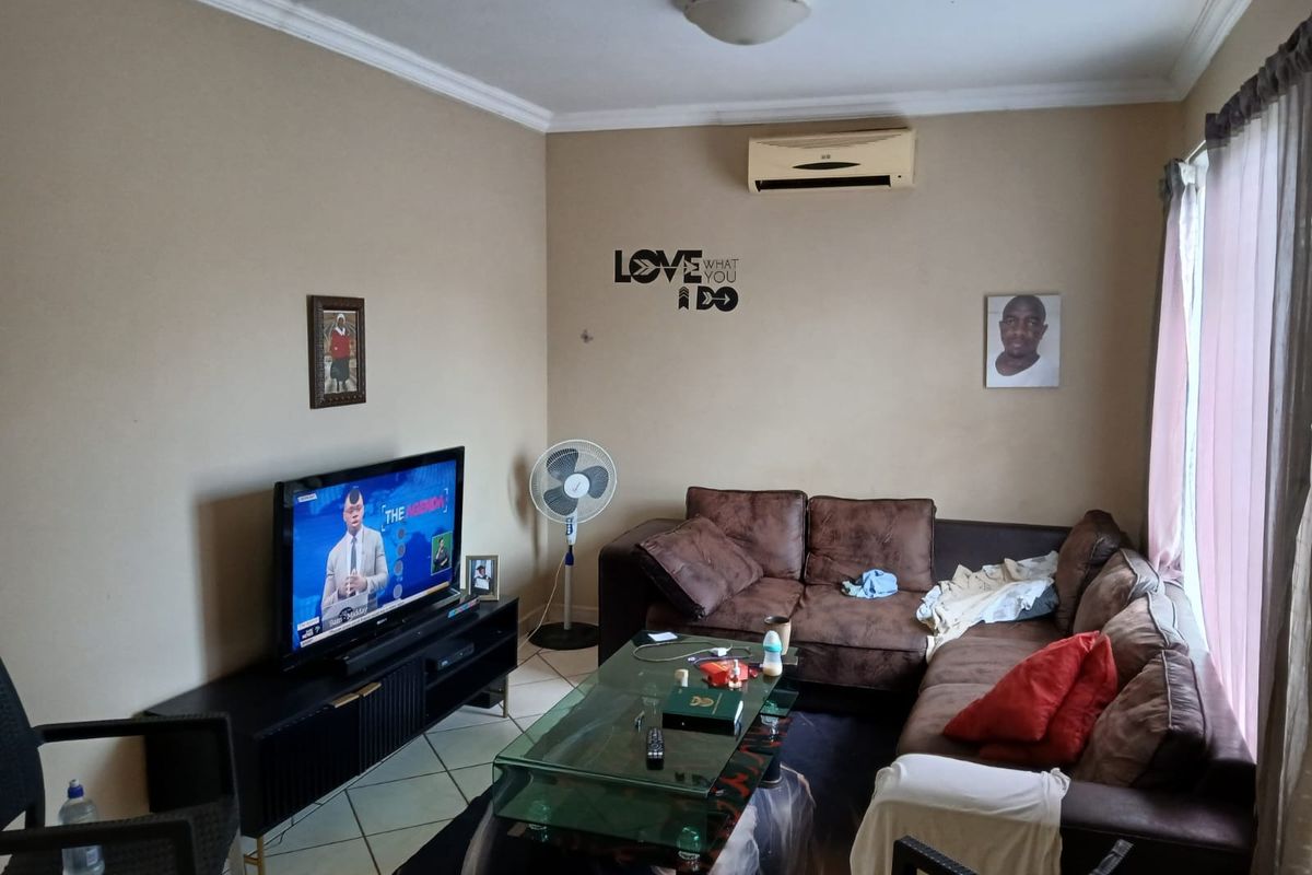 A living room featuring tiled flooring, a wall-mounted air conditioning unit, and decorative ceiling cornicing.