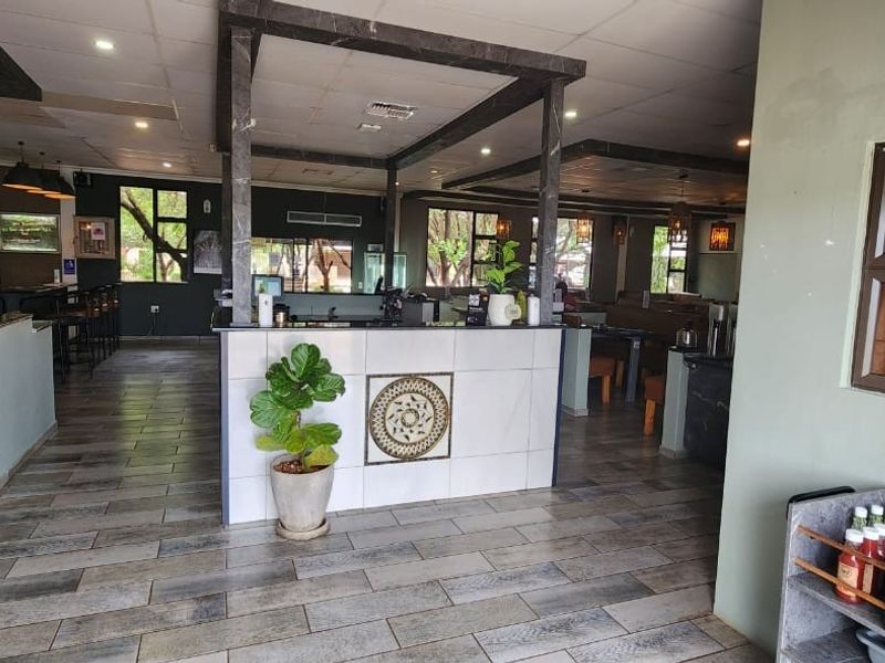 Spacious bar and lounge area featuring a central service counter, tiled flooring, and modern recessed lighting, suitable for guest house entertainment.