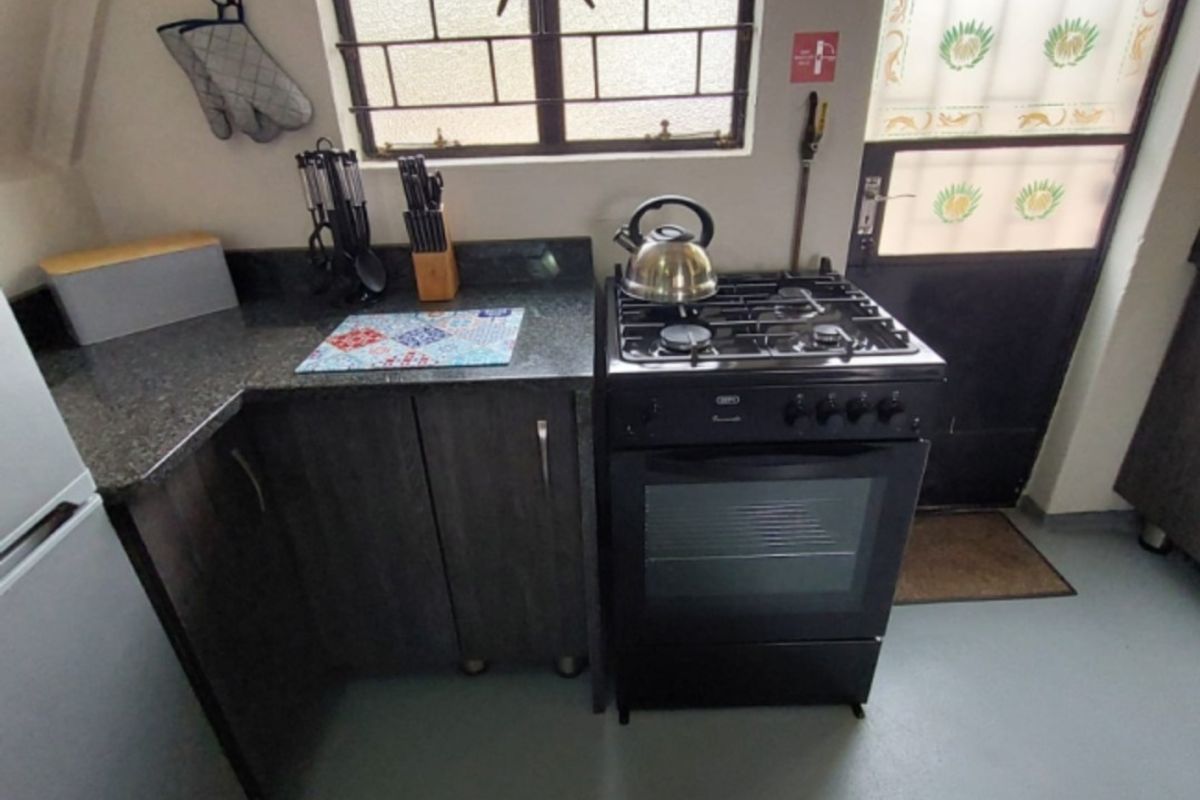 A compact kitchen featuring dark cabinetry, granite countertops, and a built-in gas stove with oven, providing a functional cooking space.