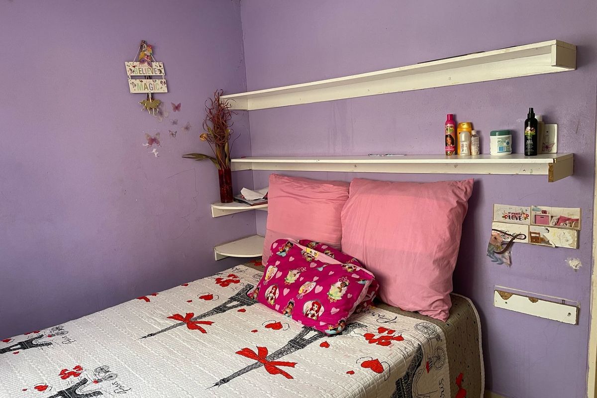 A bedroom featuring built-in wall shelving and purple painted walls, requiring cosmetic updates to improve the overall finish.