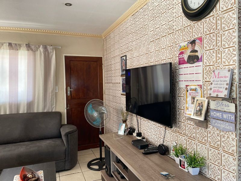 A living room featuring decorative wall tiles, crown molding, and tiled flooring, providing a functional space with a classic aesthetic.
