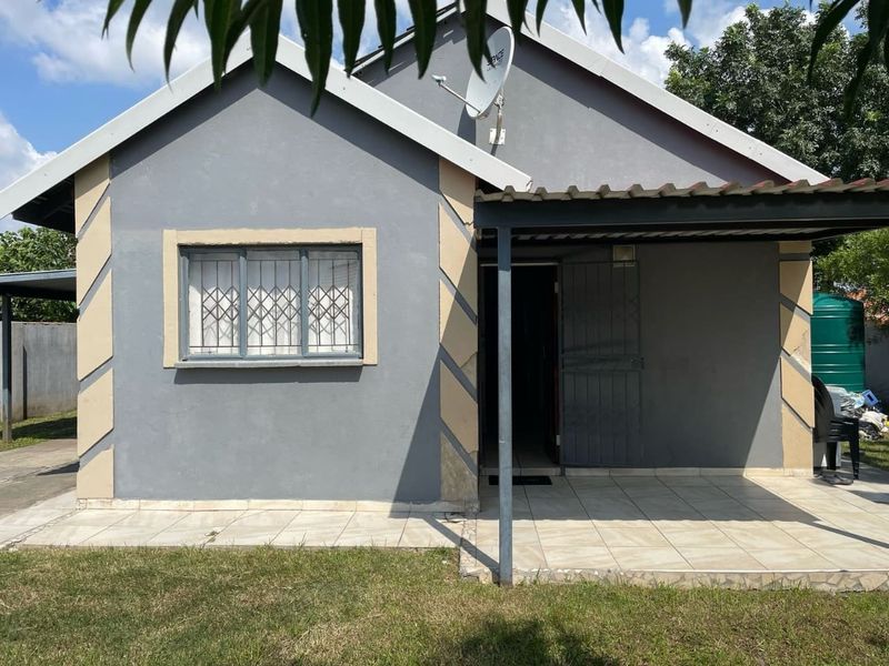 Front elevation of a single-story house featuring a tiled patio, security bars on windows, and a satellite dish installation.