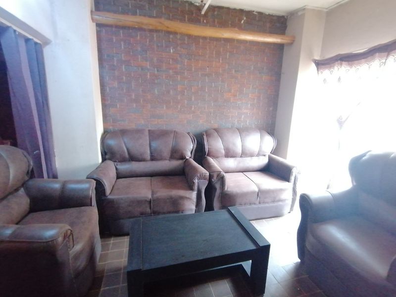 A living room featuring an exposed brick feature wall with a decorative timber beam and tiled flooring.