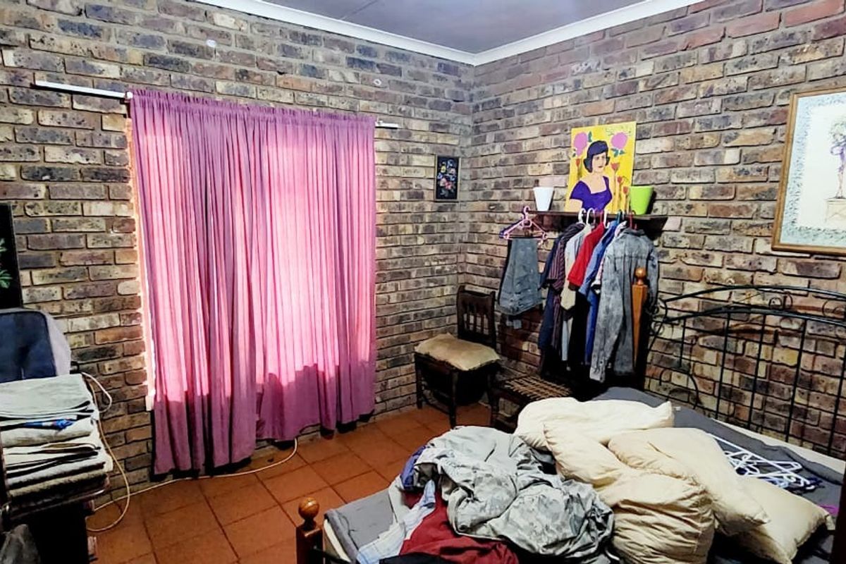A bedroom featuring exposed brick walls and tiled flooring, offering a rustic aesthetic with potential for modernization.
