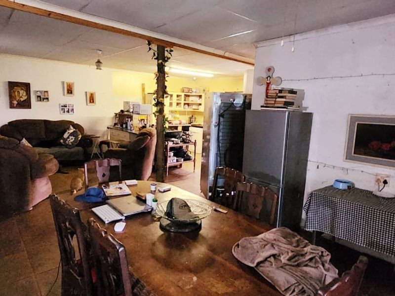 Open-plan living and dining area featuring tiled flooring and an exposed ceiling beam, connecting to a functional kitchen space.
