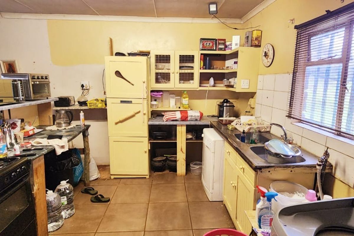 A dated kitchen featuring tiled flooring, built-in cabinetry, and a stainless steel sink, requiring cosmetic updates and modernization to improve functionality and aesthetic appeal.