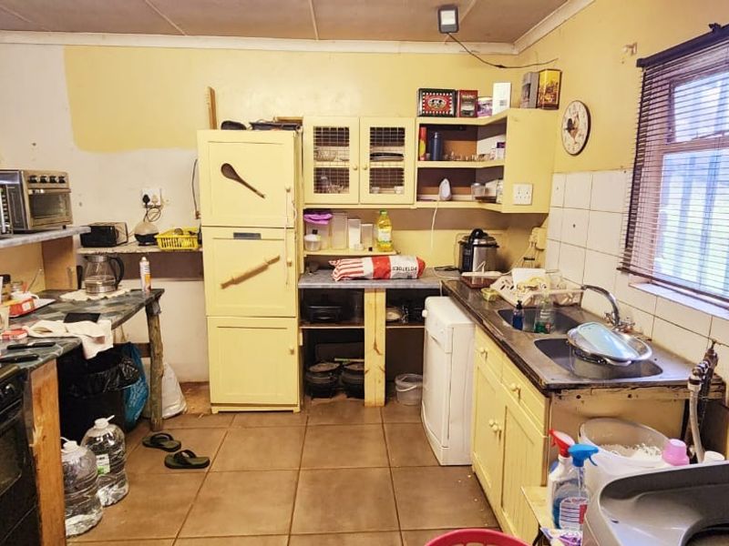 A dated kitchen featuring tiled flooring, built-in cabinetry, and a stainless steel sink, requiring cosmetic updates and modernization to improve functionality and aesthetic appeal.