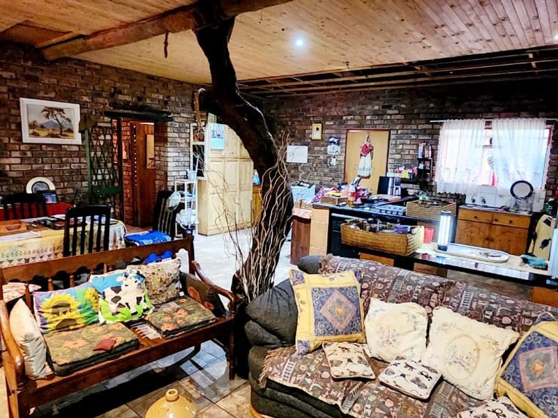 Open-plan living and kitchen area featuring rustic exposed brick walls, timber ceiling, and tiled flooring, requiring some finishing work to the ceiling.
