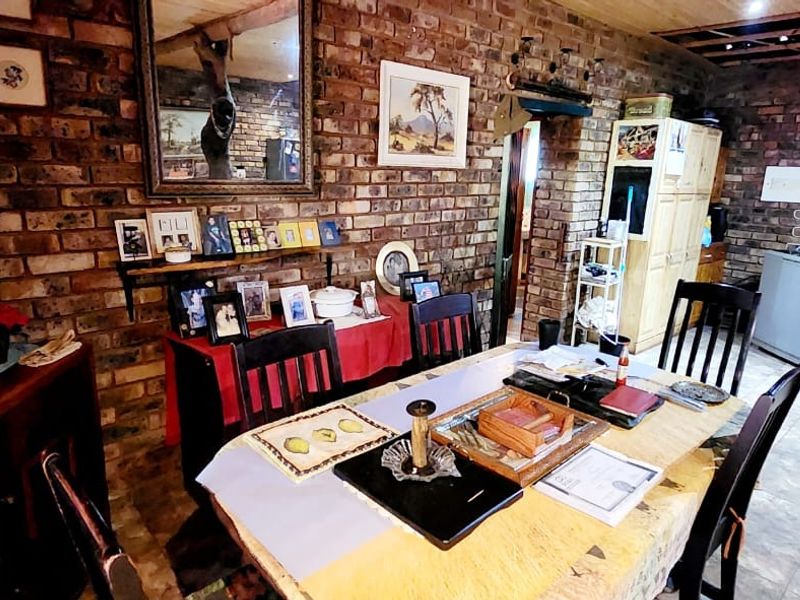 Dining area featuring rustic exposed brick walls and tiled flooring, with an unfinished timber ceiling section requiring completion.