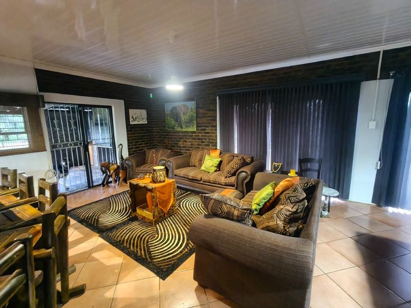 A spacious living room featuring exposed brick walls, tiled flooring, and large sliding glass doors with security gates leading to the exterior.
