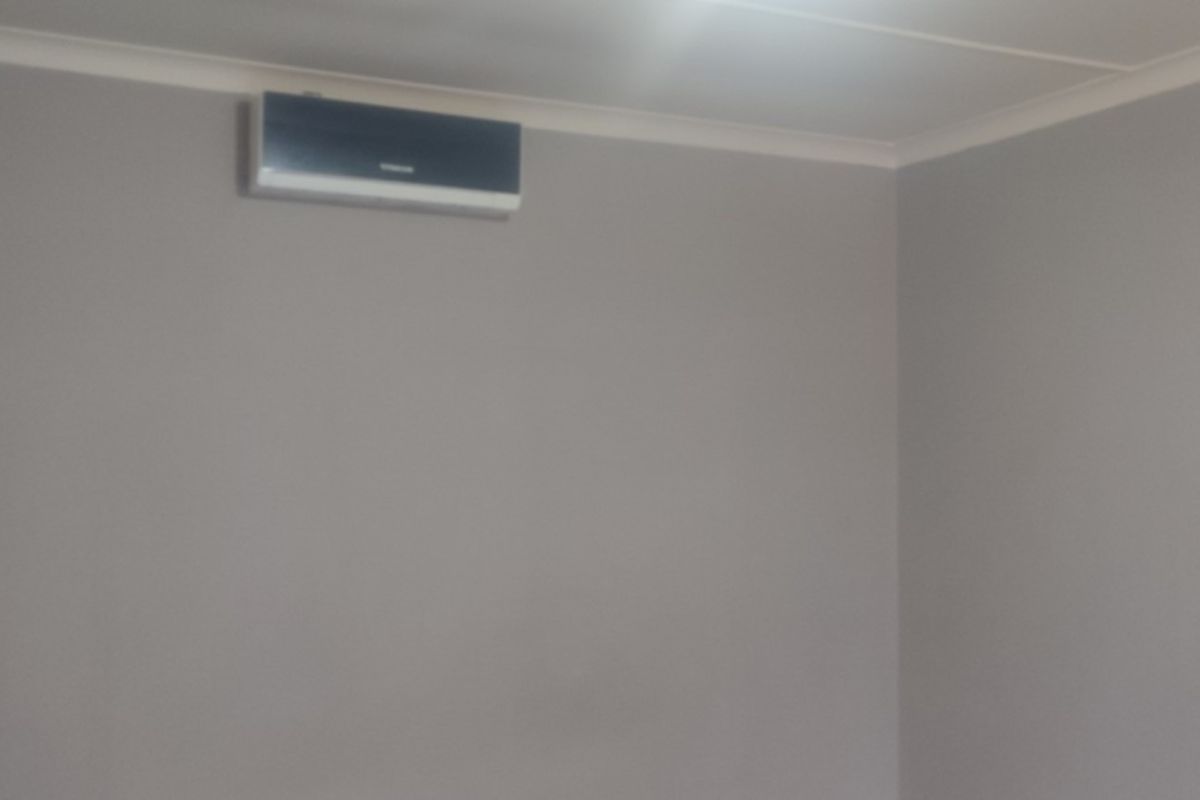 An empty room featuring neutral painted walls, coving, and a wall-mounted air conditioning unit.