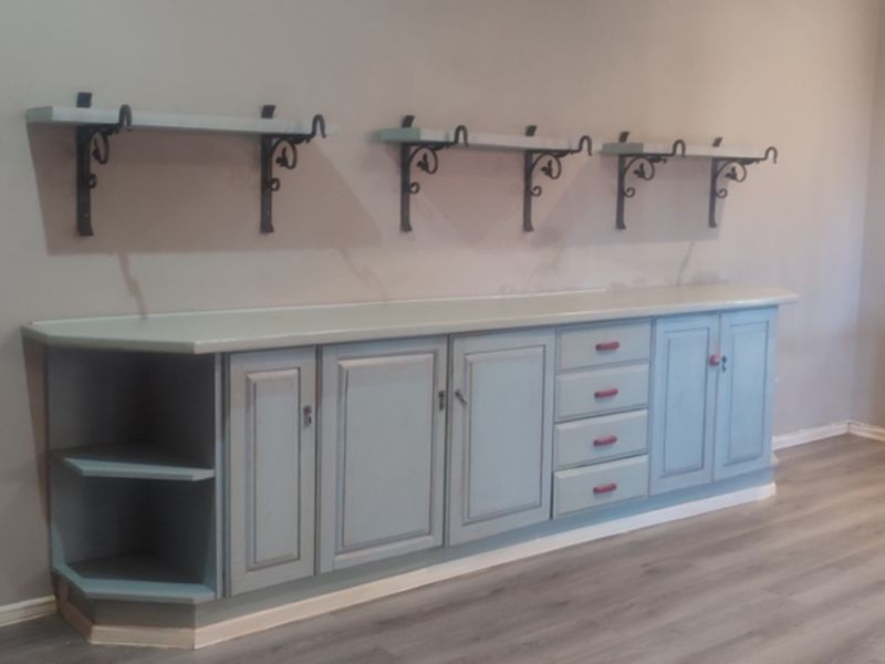 A clean utility space featuring extensive built-in cabinetry with drawers and open shelving, complemented by modern laminate flooring and neutral wall tones.