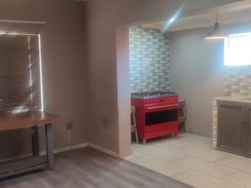 Open plan living and kitchen area featuring a red gas stove, tiled backsplash, and a mix of laminate and tiled flooring.