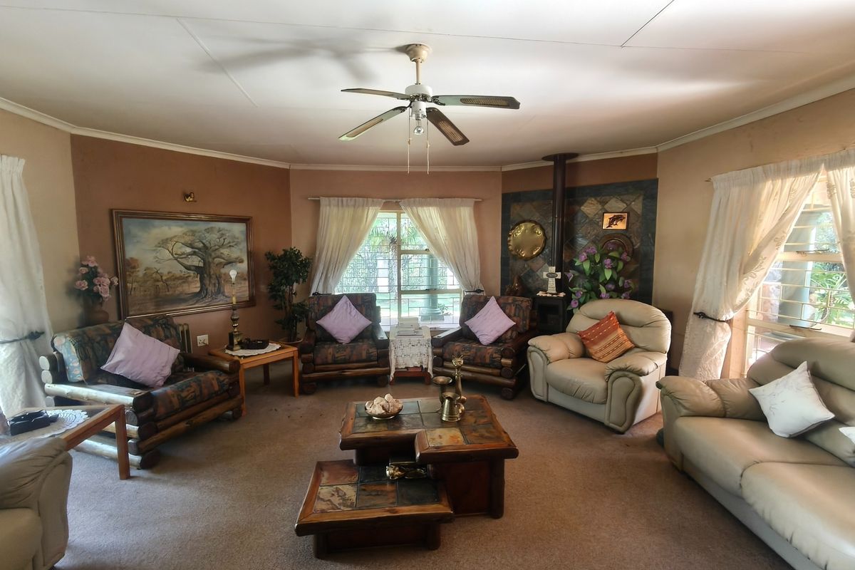 Spacious living room featuring a wood-burning stove with tiled surround, ceiling fan, and large windows with security bars.