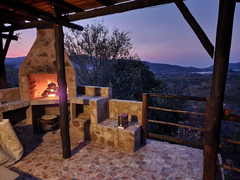 Covered outdoor patio featuring a built-in stone fireplace and scenic landscape views, perfect for evening entertaining.