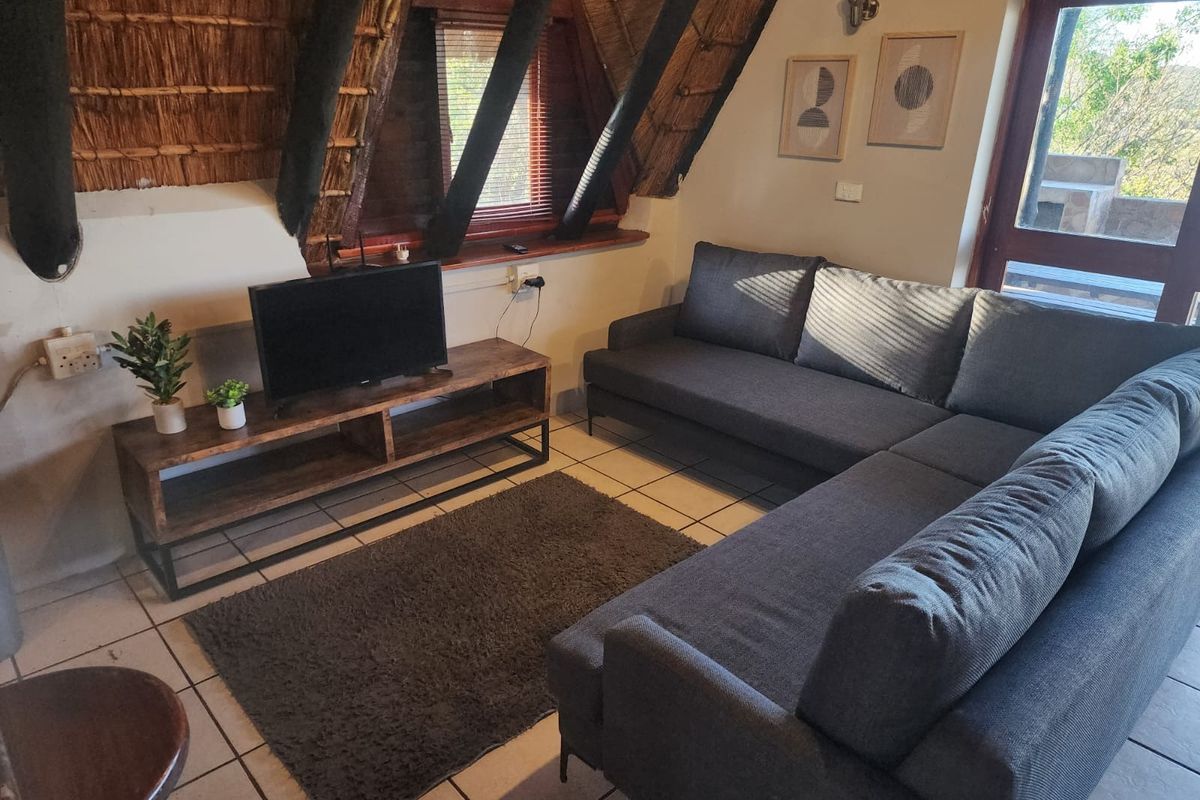 Cozy living room featuring a unique thatched roof with exposed timber rafters and tiled flooring, providing a rustic and warm atmosphere.