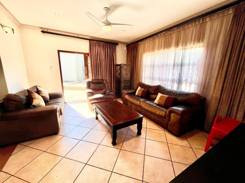 A living room featuring tiled flooring, a ceiling fan, and a sliding door providing access to the outdoor area.