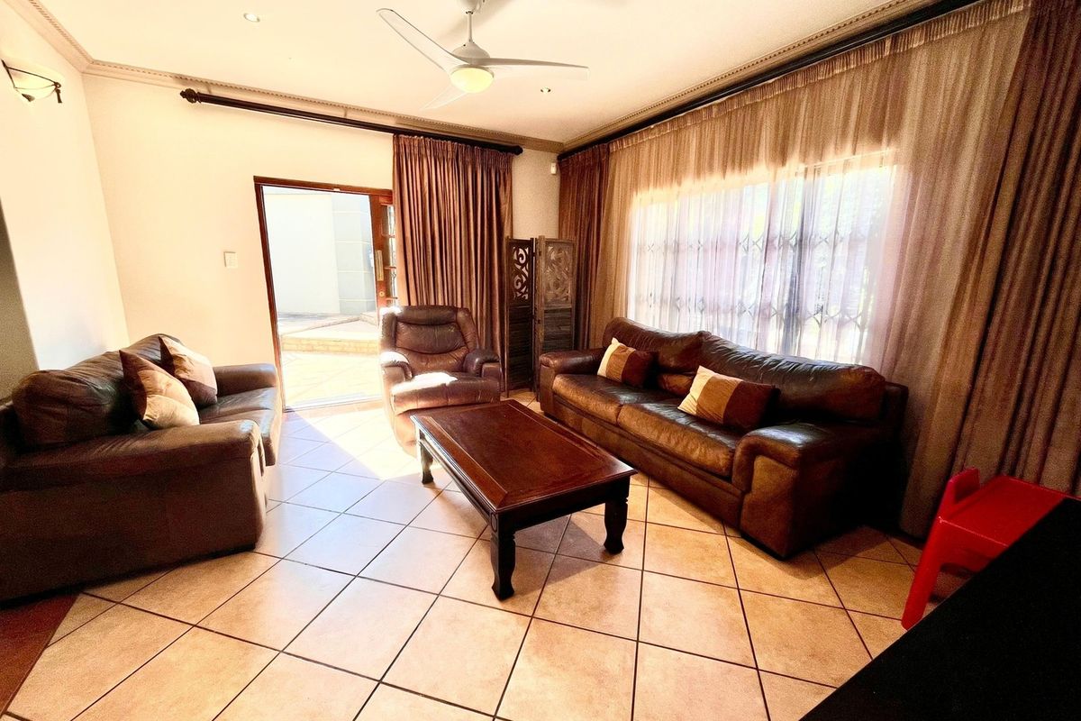 A living room featuring tiled flooring, a ceiling fan, and a sliding door providing access to the outdoor area.