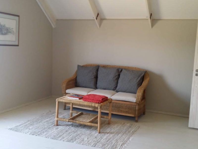 A living room featuring a vaulted ceiling with exposed rafters and neutral wall tones, providing a simple and bright living space.