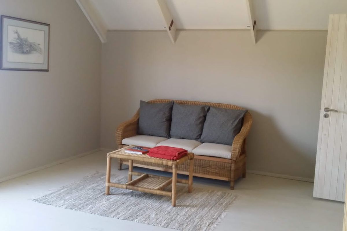 A living room featuring a vaulted ceiling with exposed rafters and neutral wall tones, providing a simple and bright living space.