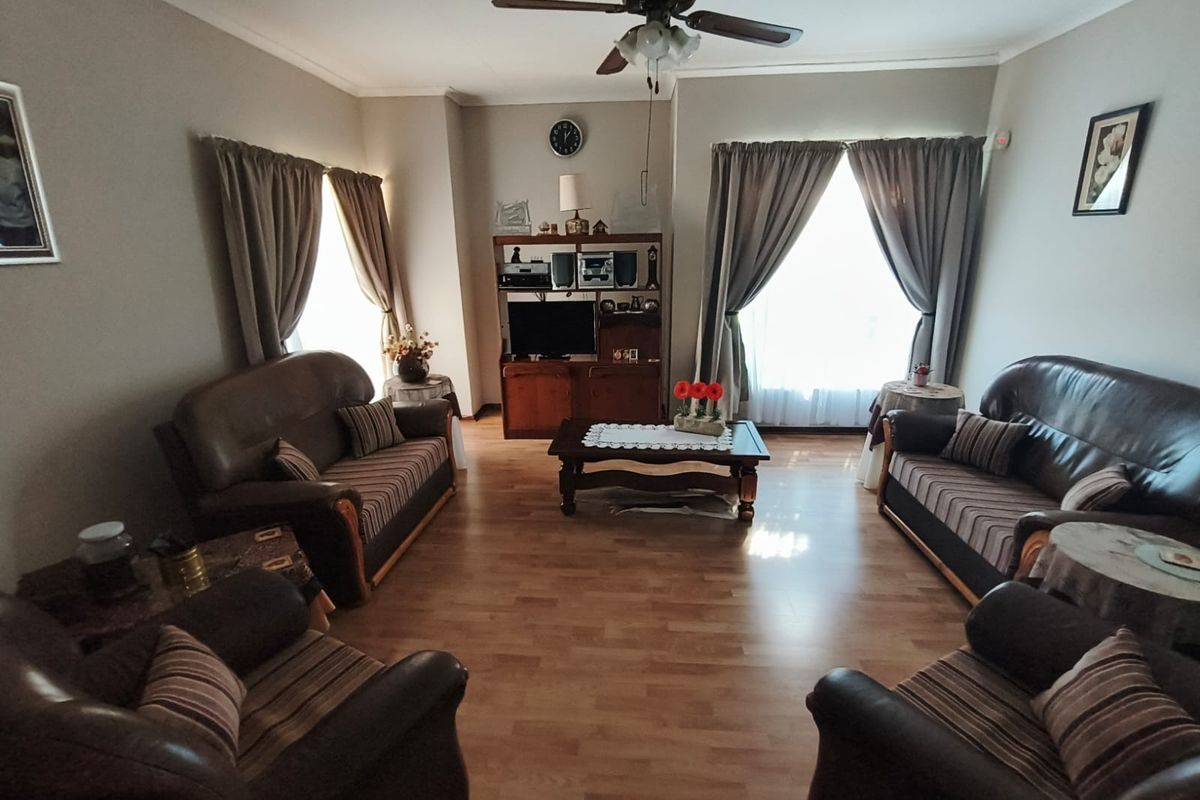 A spacious living room featuring laminate flooring and a central ceiling fan, offering a comfortable and functional layout.