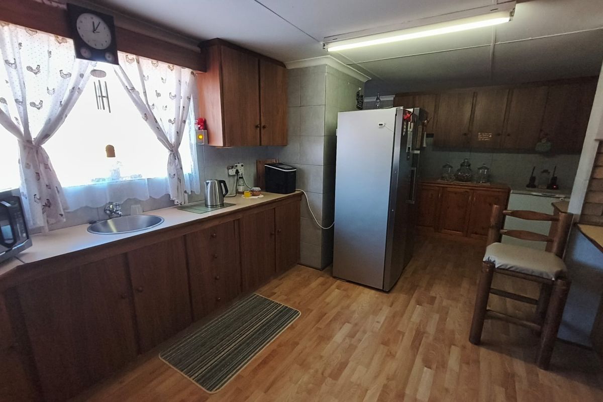 A functional kitchen featuring traditional wooden cabinetry, laminate countertops, and a stainless steel sink, offering a classic layout with ample storage space.