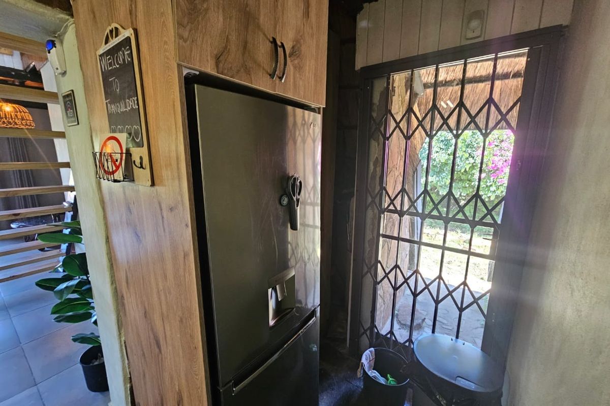 A kitchen area featuring wood-look cabinetry and a security gate leading to the exterior, with tiled flooring throughout.