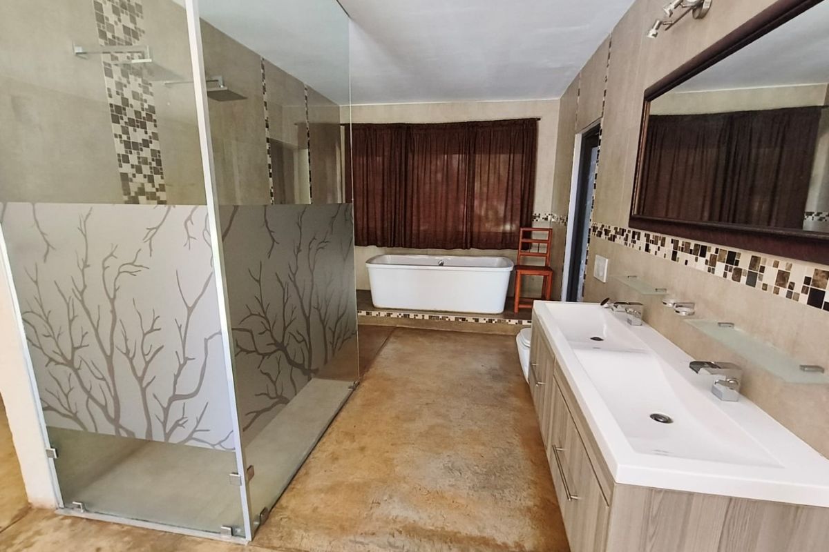 Spacious modern bathroom featuring a double vanity, a large glass-enclosed shower, and a freestanding bathtub with neutral tile finishes.
