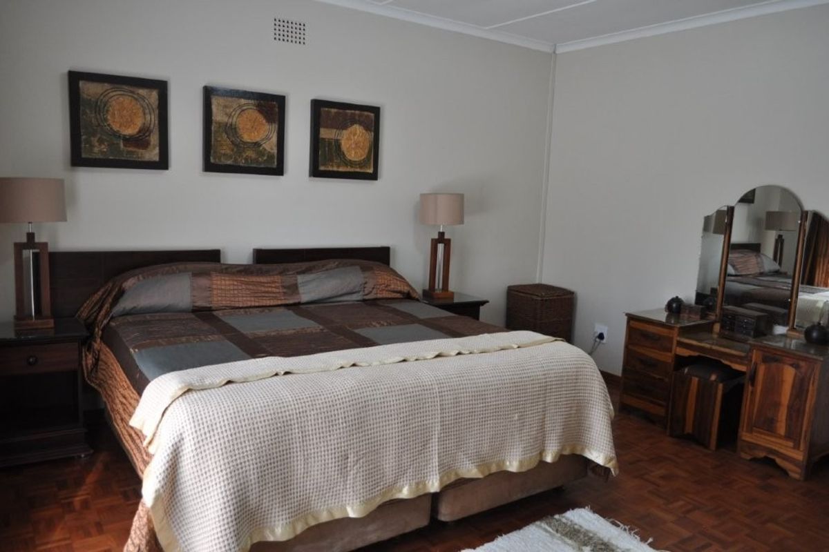 A spacious bedroom featuring warm parquet flooring and neutral wall tones, providing a comfortable and classic foundation for personal styling.