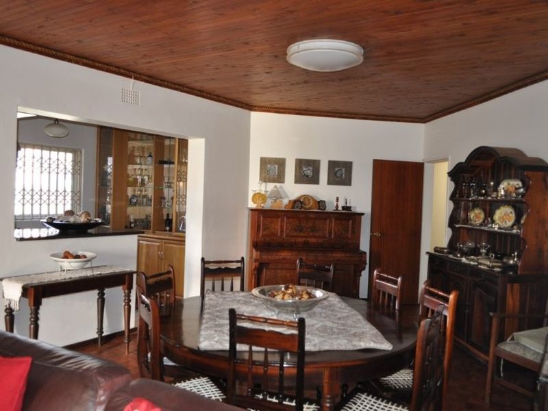 A traditional dining room featuring a warm timber ceiling, built-in display cabinetry, and a convenient serving hatch connecting to the kitchen area.