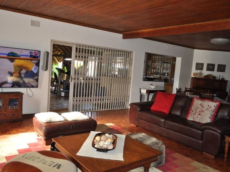 Spacious open-plan living area featuring warm parquet flooring, a classic wooden ceiling, and a built-in bar, with direct access to an outdoor patio.