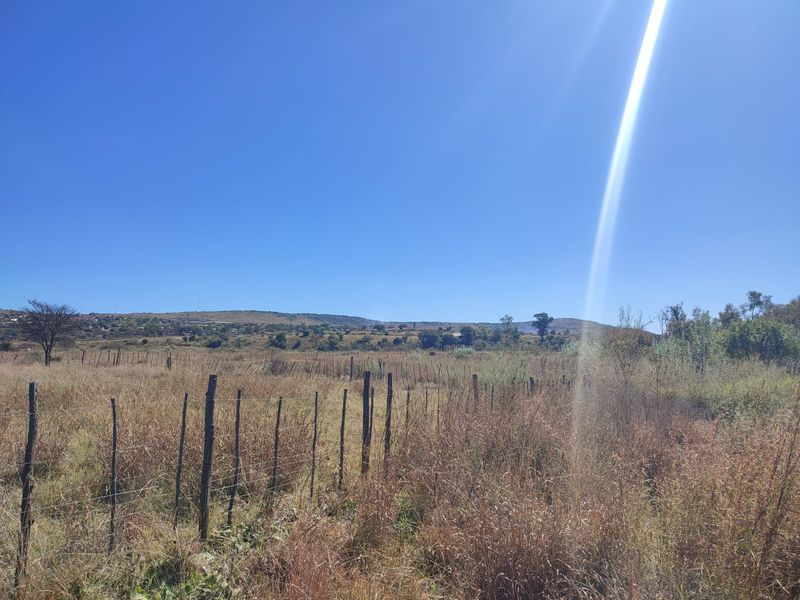 A wide-angle view of the vacant residential land featuring natural landscape, dry vegetation, and perimeter wire fencing with wooden posts.
