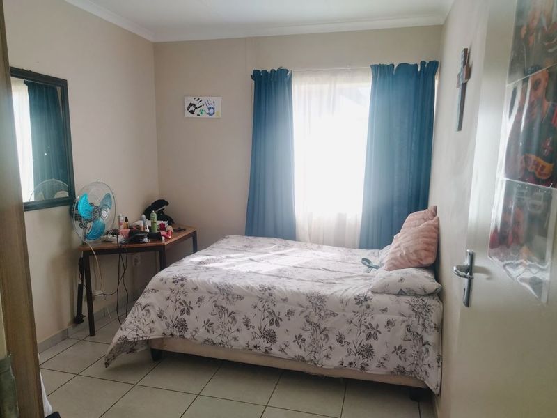 A standard bedroom featuring tiled flooring and a window with curtain rails, providing a functional and neutral living space.