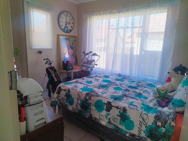 A functional bedroom featuring tiled flooring, a built-in cupboard, and large windows with venetian blinds, offering a bright and practical living space.