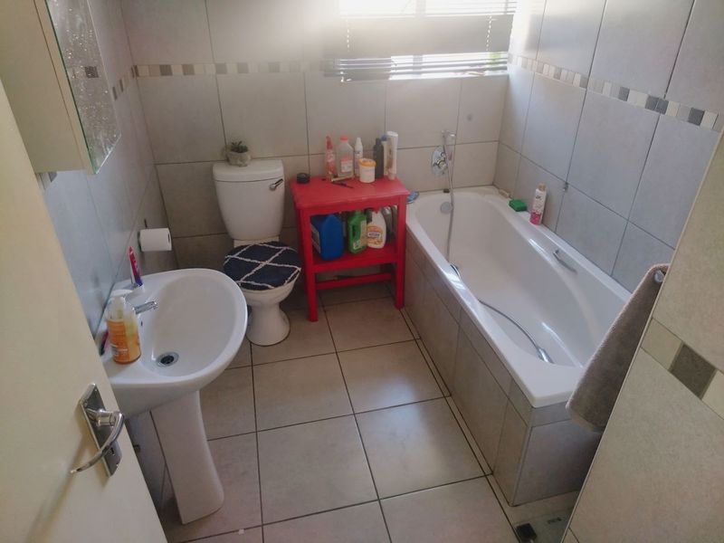 A functional bathroom featuring a pedestal basin, toilet, and bathtub with tiled finishes throughout.