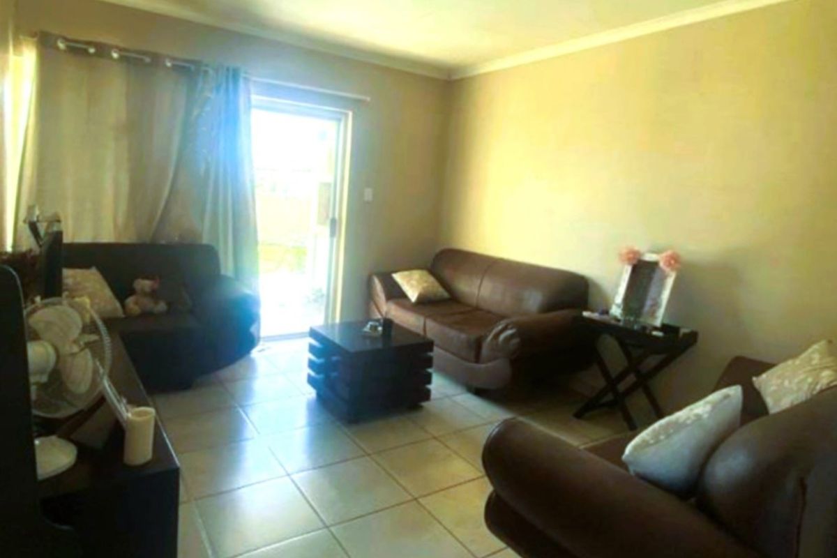 A living room featuring tiled flooring and a sliding glass door providing access to the exterior.