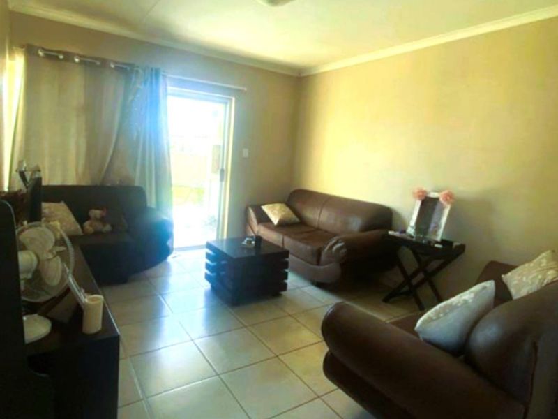 A living room featuring tiled flooring and a sliding glass door providing access to the exterior.
