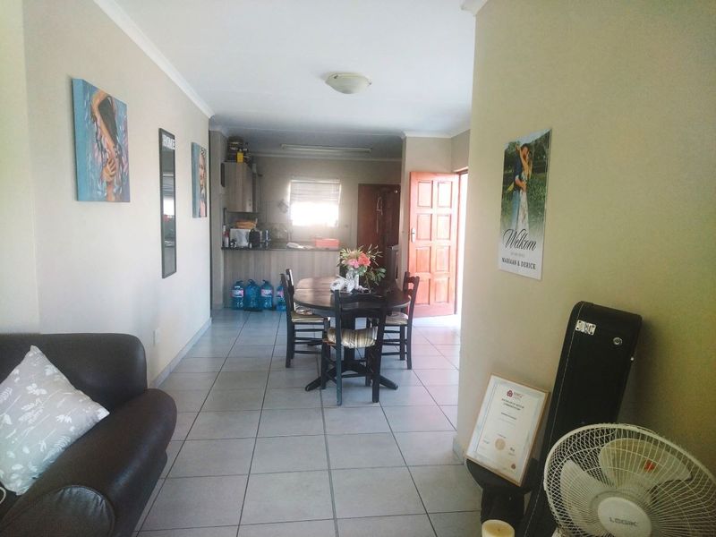 An open-plan living and dining area featuring tiled flooring, leading into a kitchen space with built-in cabinetry and a breakfast counter.