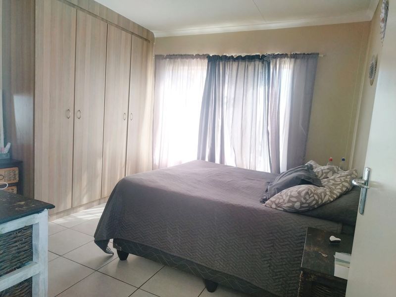 A bedroom featuring built-in cupboards and tiled flooring, offering a functional space with natural light.