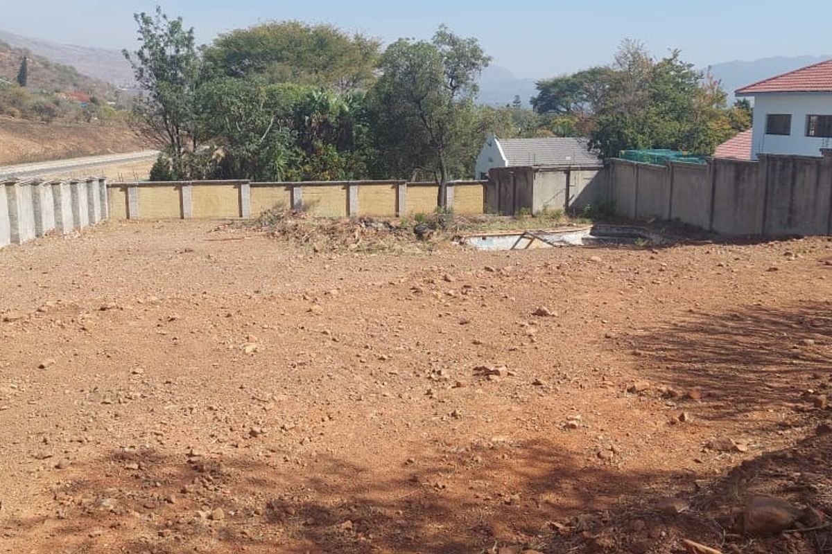 A vacant residential plot featuring a perimeter wall and an existing, non-functional swimming pool structure.