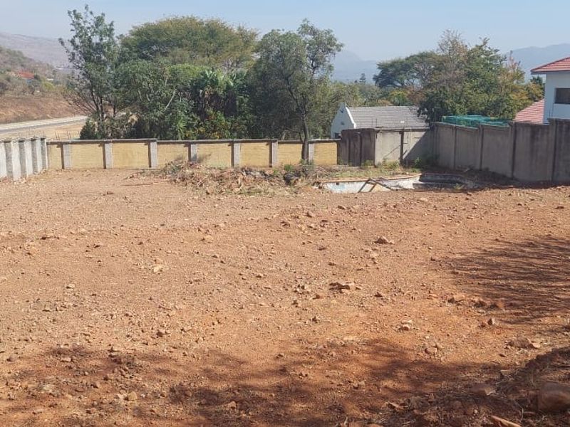 A vacant residential plot featuring a perimeter wall and an existing, non-functional swimming pool structure.
