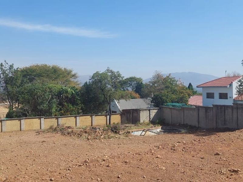 A vacant residential plot featuring a perimeter wall, barbed wire fencing, and an existing in-ground pool shell requiring significant restoration.