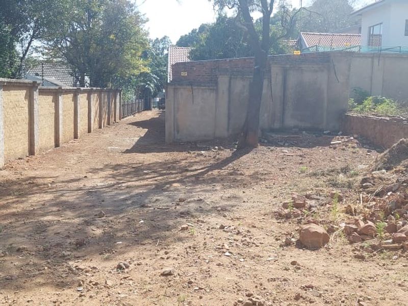 A vacant residential plot featuring perimeter boundary walls and a retaining wall, with cleared ground ready for development.