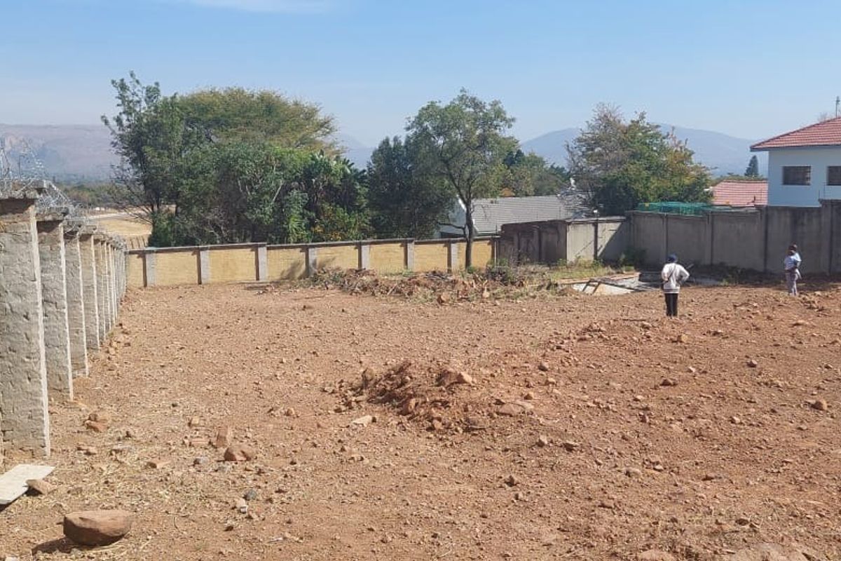 A vacant residential plot featuring a perimeter wall with security razor wire, offering a clear space for future development.